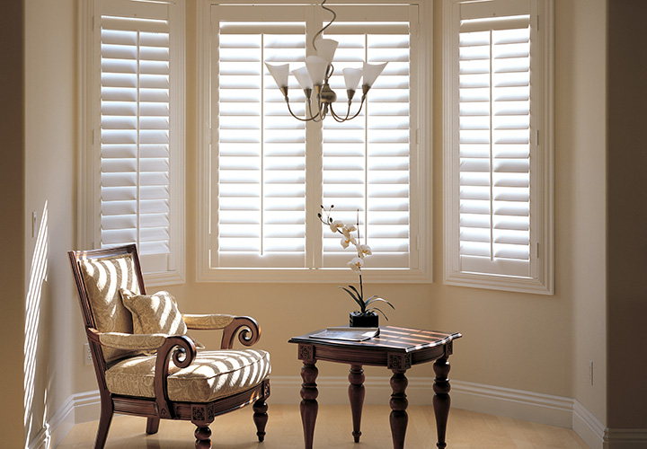 Bay window shutters in lounge room with chair and table